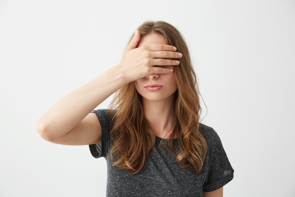 Chica de pelo largo tapándose los ojos con una mano