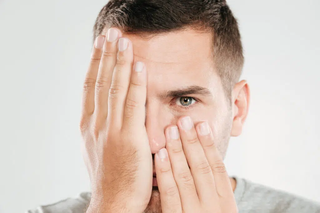 Chico tapandose un ojo con una mano y con la otra parte de la cara